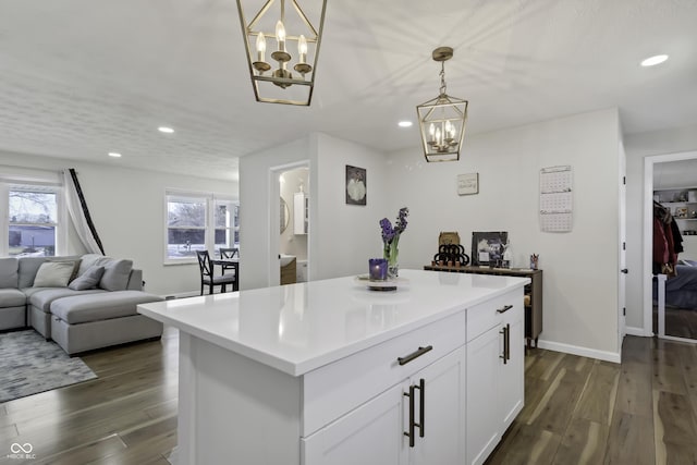 kitchen with a kitchen island, dark wood-type flooring, pendant lighting, and white cabinets