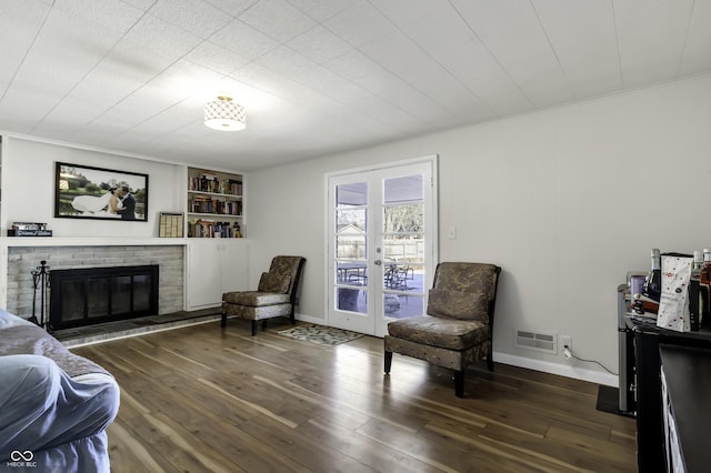 sitting room featuring ornamental molding, dark hardwood / wood-style floors, a fireplace, and french doors