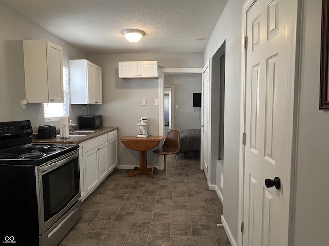kitchen with white cabinetry, electric range, and a textured ceiling