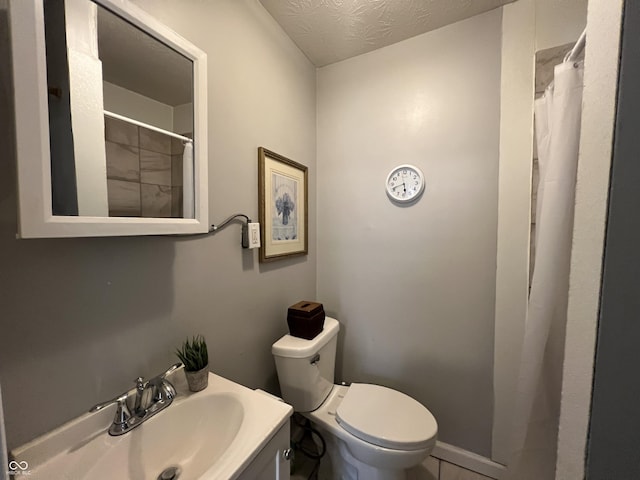 bathroom with vanity, toilet, and a textured ceiling