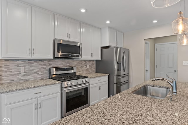 kitchen featuring pendant lighting, sink, stainless steel appliances, and white cabinets