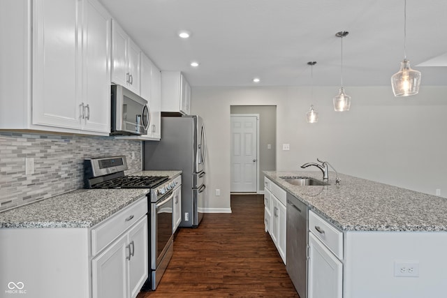 kitchen with appliances with stainless steel finishes, white cabinets, light stone counters, and decorative light fixtures