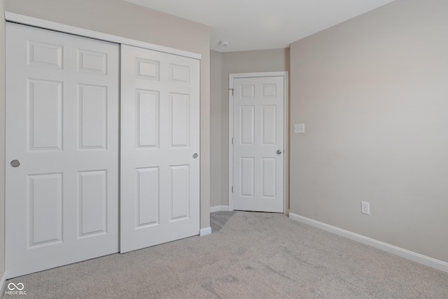 unfurnished bedroom with light carpet and a closet