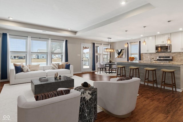 living room featuring a raised ceiling and dark wood-type flooring