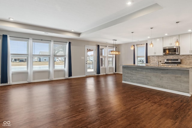 unfurnished living room with a tray ceiling, dark hardwood / wood-style flooring, and sink