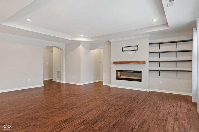 unfurnished living room with a tray ceiling and dark wood-type flooring