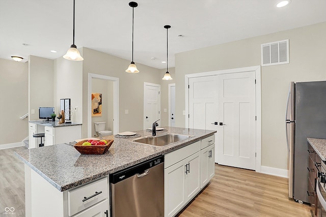 kitchen featuring appliances with stainless steel finishes, sink, an island with sink, and white cabinets