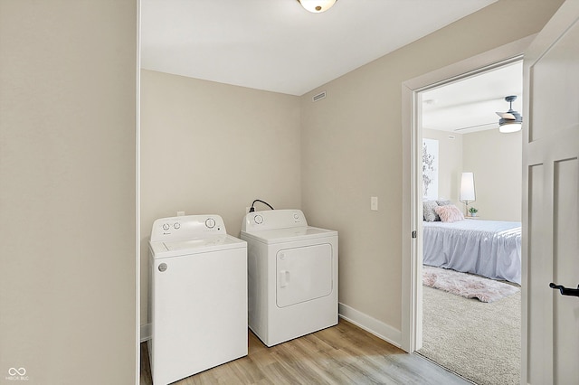 laundry area with ceiling fan, light hardwood / wood-style floors, and washing machine and dryer