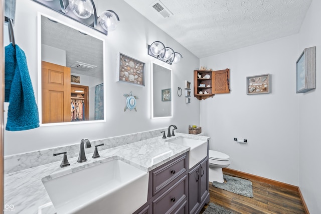 bathroom featuring vanity, hardwood / wood-style flooring, toilet, and a textured ceiling