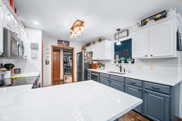 kitchen with sink, tasteful backsplash, appliances with stainless steel finishes, pendant lighting, and white cabinets