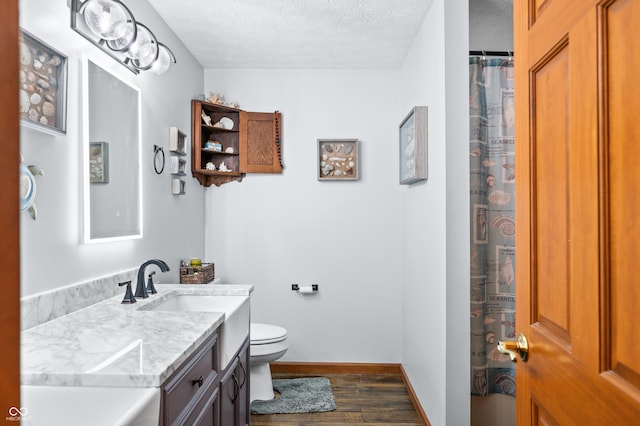 bathroom featuring vanity, hardwood / wood-style flooring, toilet, and a textured ceiling