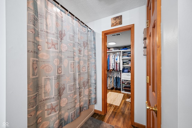 bathroom with shower / bathtub combination with curtain, hardwood / wood-style flooring, and a textured ceiling