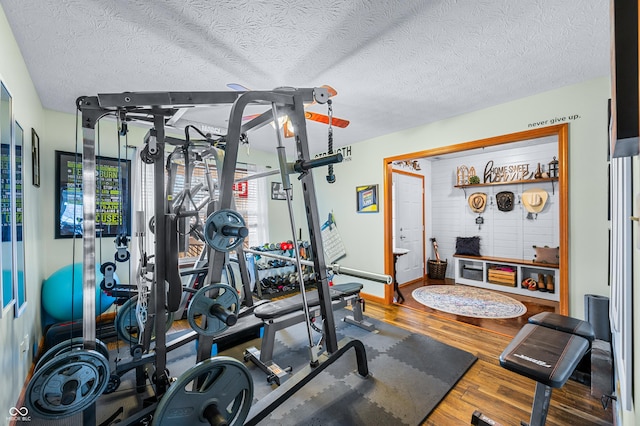 exercise room with hardwood / wood-style floors and a textured ceiling