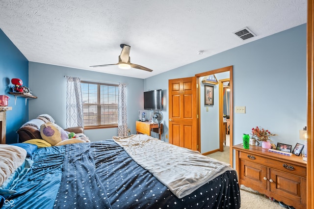 bedroom with a textured ceiling, light colored carpet, and ceiling fan