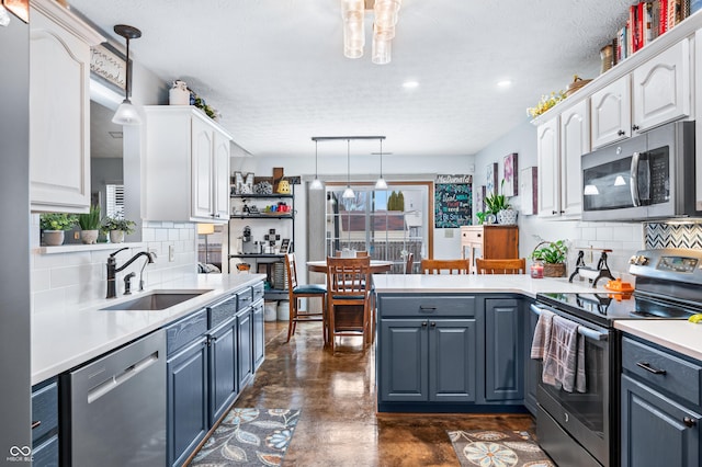 kitchen featuring decorative light fixtures, white cabinetry, sink, kitchen peninsula, and stainless steel appliances