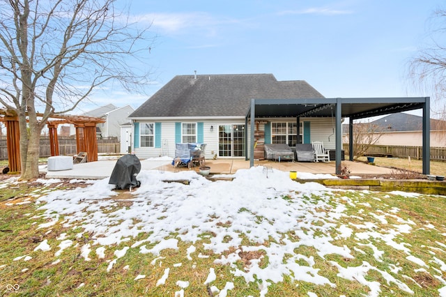 snow covered back of property with a pergola and a patio area