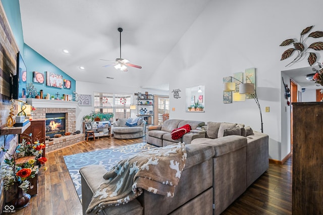 living room with dark wood-type flooring, ceiling fan, high vaulted ceiling, and a brick fireplace