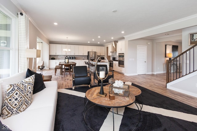 living room featuring crown molding, a notable chandelier, and light wood-type flooring