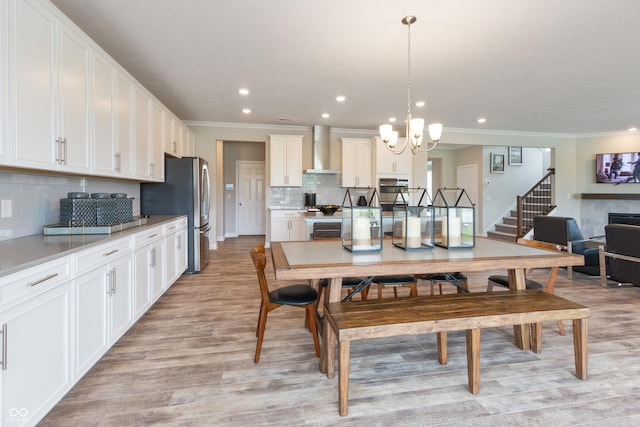 dining area featuring crown molding, light hardwood / wood-style flooring, and a notable chandelier