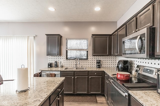 kitchen with stainless steel appliances, light stone countertops, sink, and decorative backsplash