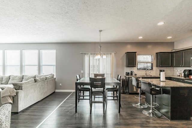 dining space featuring plenty of natural light, dark hardwood / wood-style flooring, sink, and a textured ceiling