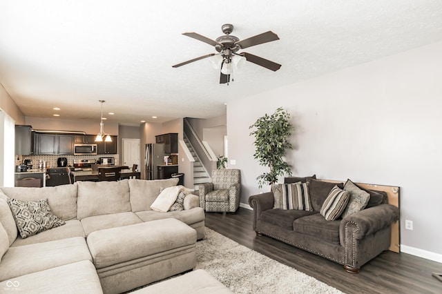 living room featuring ceiling fan, dark hardwood / wood-style flooring, and a textured ceiling