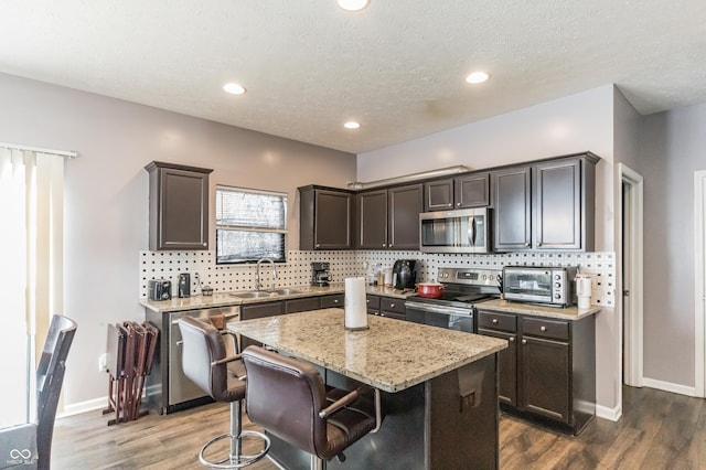 kitchen with a kitchen island, tasteful backsplash, sink, stainless steel appliances, and light stone countertops