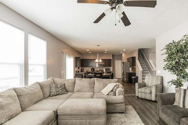 living room with dark wood-type flooring, ceiling fan, and a textured ceiling