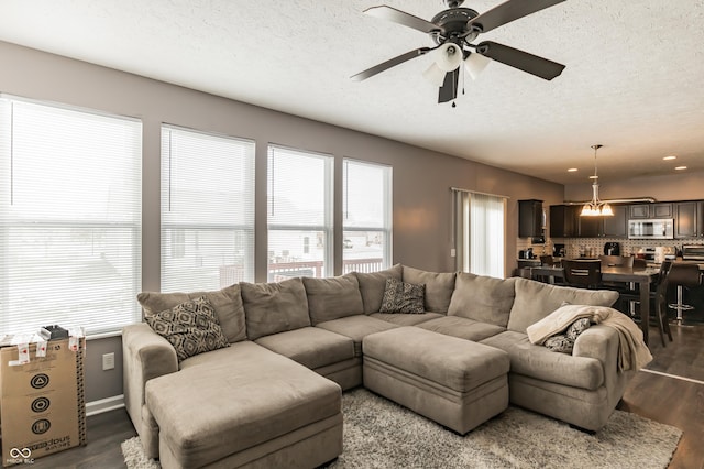 living room with ceiling fan, dark wood-type flooring, and a textured ceiling