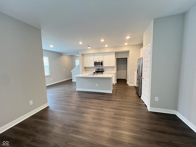 kitchen with sink, white cabinetry, a center island with sink, appliances with stainless steel finishes, and dark hardwood / wood-style floors