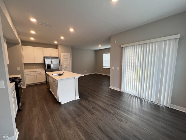 kitchen featuring an island with sink, dark hardwood / wood-style floors, white cabinets, and gas range oven