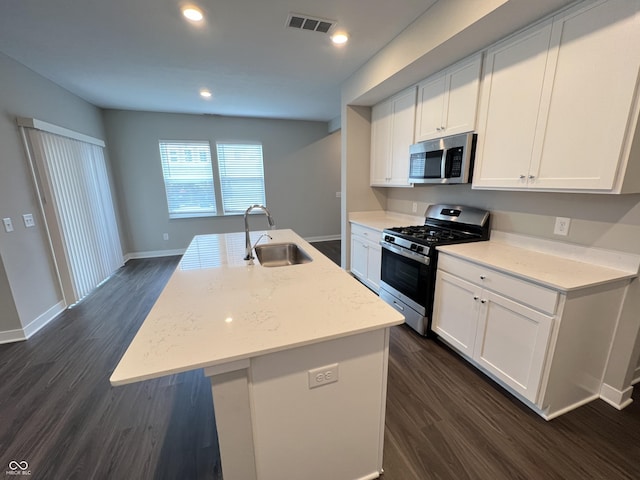 kitchen with sink, appliances with stainless steel finishes, light stone counters, white cabinets, and a center island with sink