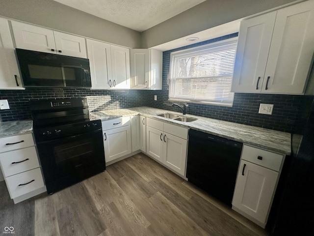 kitchen with sink, wood-type flooring, black appliances, and white cabinets