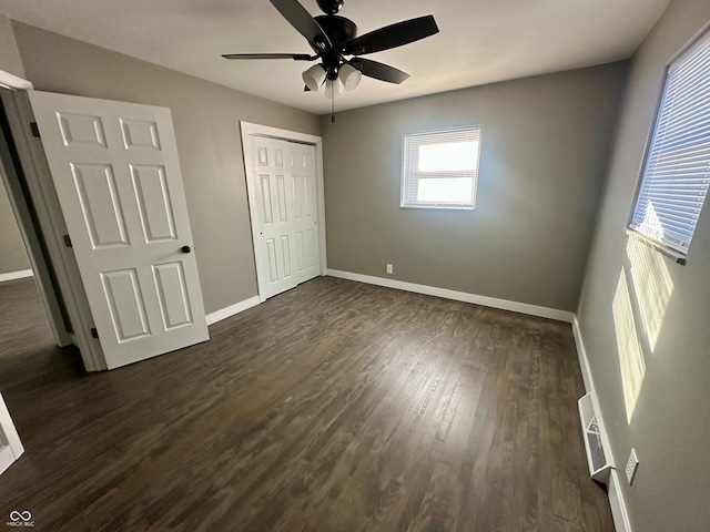 unfurnished bedroom featuring ceiling fan, dark hardwood / wood-style flooring, and a closet