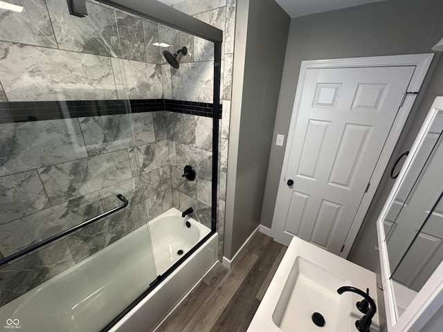 bathroom featuring sink, wood-type flooring, and enclosed tub / shower combo