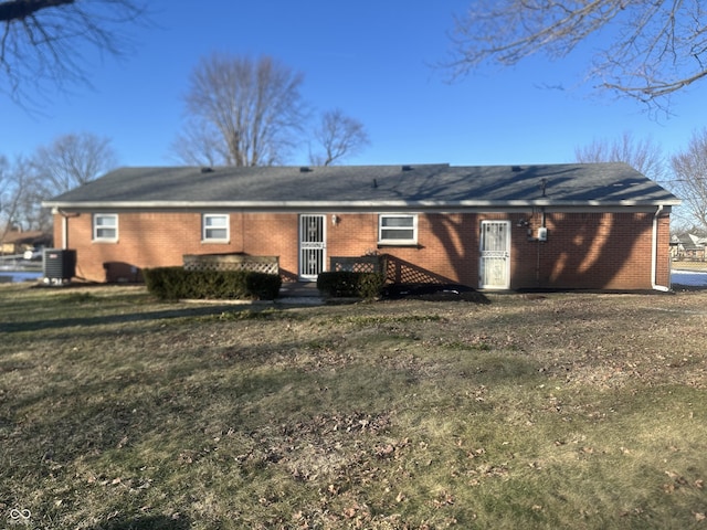 back of property with central AC and a lawn