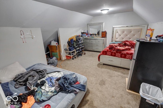 bedroom with lofted ceiling, stainless steel fridge, and light colored carpet