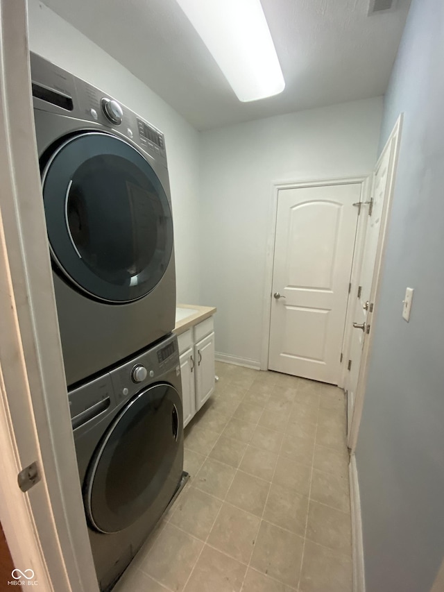 clothes washing area with cabinets and stacked washer / dryer