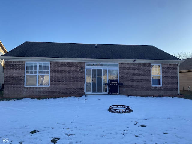 snow covered back of property with a fire pit