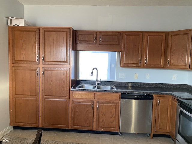 kitchen featuring dark stone countertops, sink, light tile patterned flooring, and appliances with stainless steel finishes