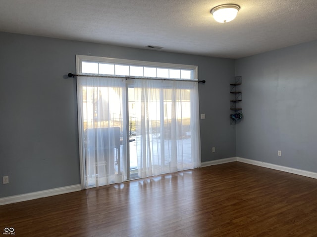 spare room with a textured ceiling and dark hardwood / wood-style flooring