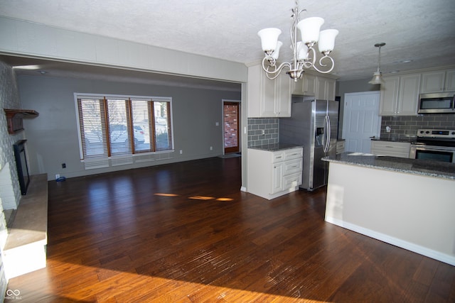 kitchen featuring a fireplace, appliances with stainless steel finishes, decorative light fixtures, and dark hardwood / wood-style flooring