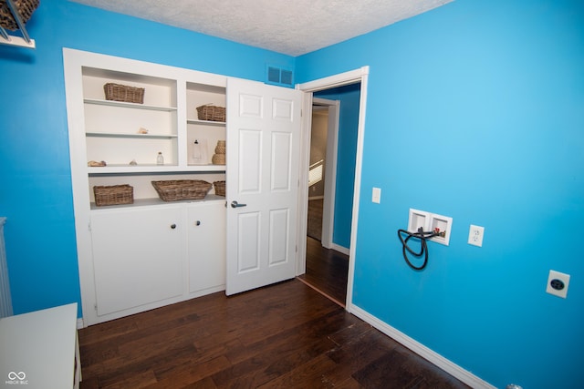 clothes washing area featuring dark wood-type flooring, cabinets, a textured ceiling, hookup for a washing machine, and hookup for an electric dryer