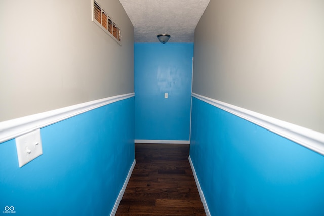 hall featuring dark wood-type flooring and a textured ceiling