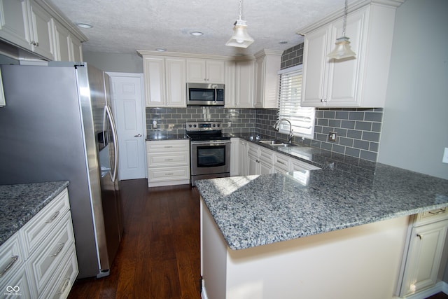 kitchen with hanging light fixtures, sink, kitchen peninsula, and appliances with stainless steel finishes