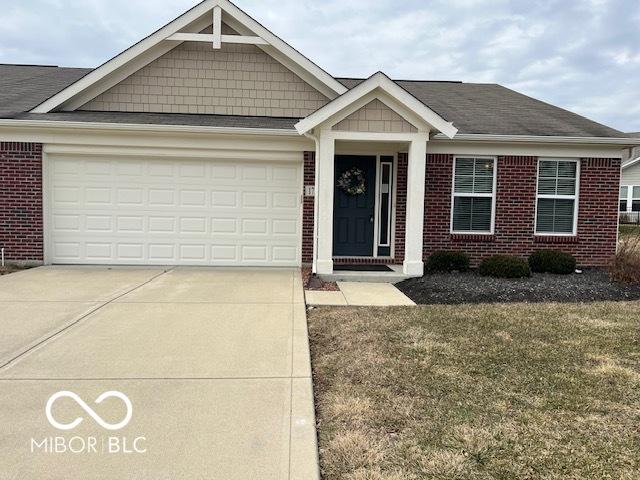 view of front facade with driveway, a garage, a front lawn, and brick siding