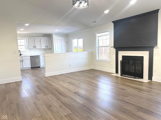 unfurnished living room featuring sink, a fireplace, and hardwood / wood-style floors