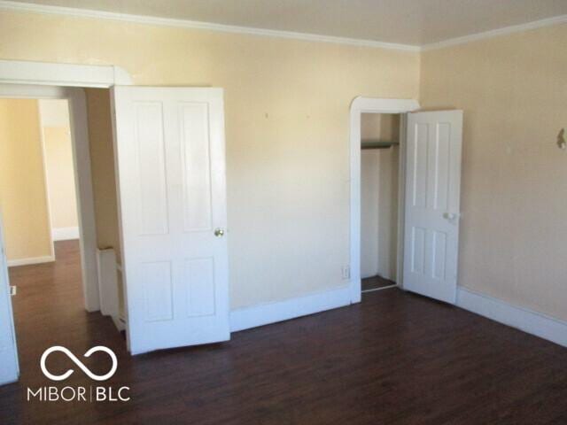 unfurnished bedroom featuring dark wood-type flooring and ornamental molding