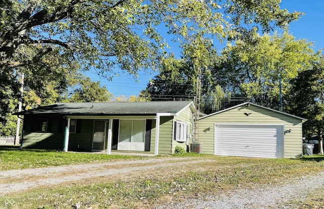 view of front facade featuring covered porch, cooling unit, a garage, an outdoor structure, and a front yard