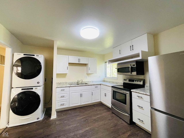 kitchen featuring sink, stacked washing maching and dryer, stainless steel appliances, light stone countertops, and white cabinets